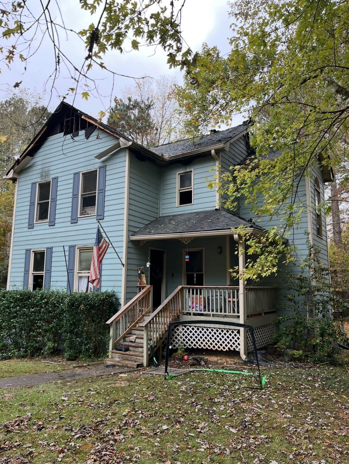 Home exterior with fire-damaged roof and siding